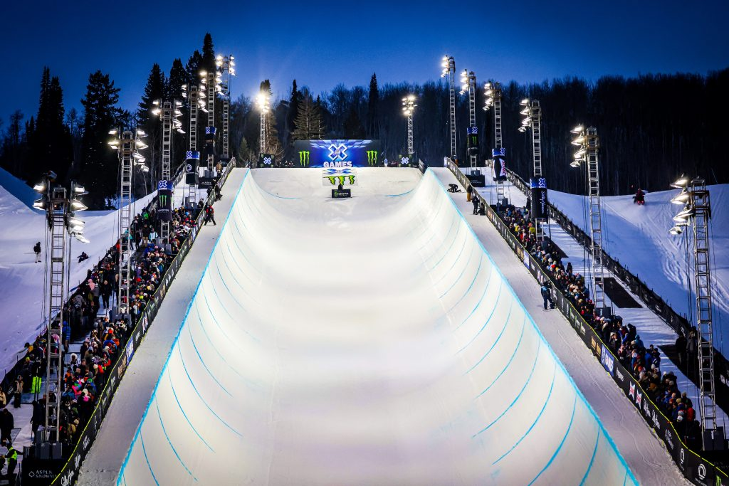 The floodlit X Games Aspen SuperPipe at night, lined with spectators