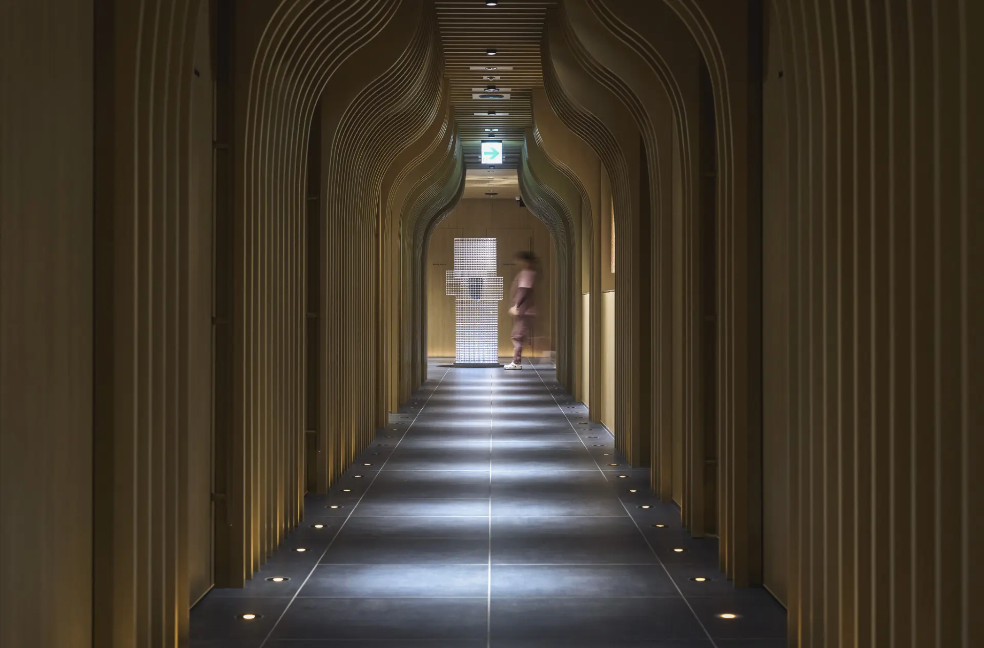 A softly lit, sculpted timber corridor inside a Tokyo regenerative medicine clinic